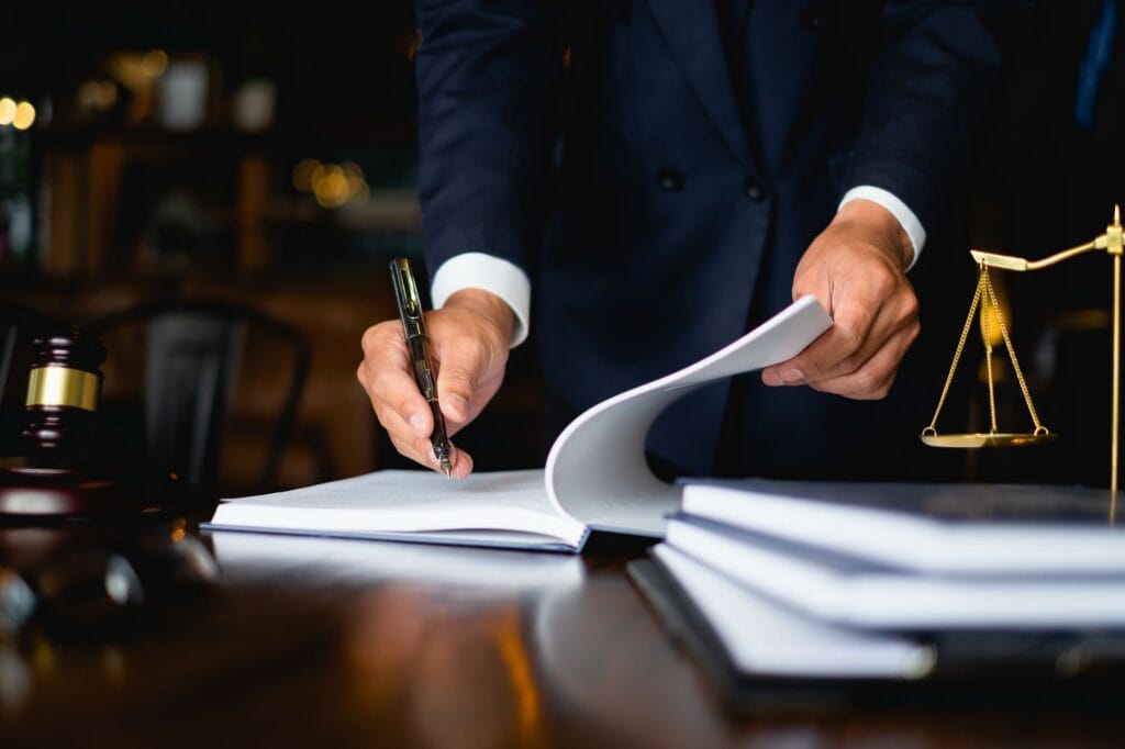 Lawyer signing legal documents with a pen in a law office setting.